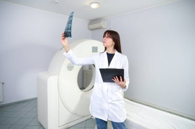Genç bayan radyologlar tomografi odasında kalıyorlar. Klinikte çalışıyorum. Güzel doktor MRI taramasına bakıyor. Beyaz takım elbiseli bir doktor. Üniformalı Radyolog.