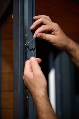 Yeni bir inşaat sahasına kapı ve pencere döşeyen işçilerin yakın görüntüsü. Büyülü anahtarı olan üniformalı bir adam yeni güzel evin ön cam kapısını ve pencerelerini ayarlıyor. Ekin görünümü.