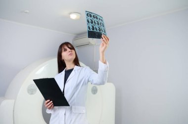 Genç bayan radyologlar tomografi odasında kalıyorlar. Klinikte çalışıyorum. Güzel doktor MRI taramasına bakıyor. Beyaz takım elbiseli bir doktor. Üniformalı Radyolog.