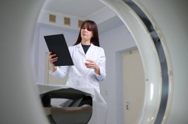 Genç bayan radyologlar tomografi odasında kalıyorlar. Klinikte çalışıyorum. Güzel doktor röntgen, röntgen, tomografi ve MRI 'ya bakıyor. Üniformalı doktor.