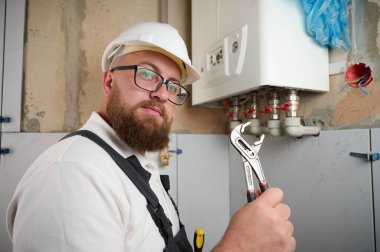 Tesisatçı bir kazan kurdu. Profesyonel mühendis eve gaz kazanı kuruyor ve iç ısıtma sisteminin bağlantılarını ve borularını kontrol ediyor. Isıtma sistemini ayarlayan Kazan Kurma Servisi.