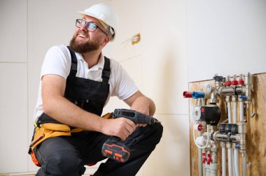 Adam yeni bir dairede ısıtma sistemini ayarlıyor. Tesisatçı merkezi sistem vanalarındaki ısıyı ayarlıyor. Servis elemanı ısıtma sistemini ayarlıyor. Yeraltı ısıtma sistemi. Adam boruyu kontrol ediyor