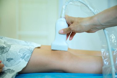 Pediatrik ultrason taraması. Çocuk ultrasonu. Çocuk doktoru bacağını tarıyor. Doktorun çocuk için bacak sonogramı yapmasına yakın çekim. İskelet sisteminin ultrason incelemesi. Eklem hastalıkları konsepti