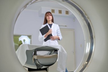 Genç bayan radyologlar tomografi odasında kalıyorlar. Klinikte çalışıyorum. Güzel doktor röntgen, röntgen, tomografi ve MRI 'ya bakıyor. Üniformalı doktor.