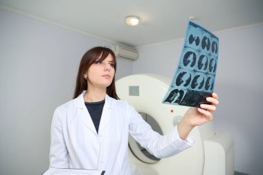 Genç bayan radyologlar tomografi odasında kalıyorlar. Klinikte çalışıyorum. Güzel doktor röntgen, röntgen, tomografi ve MRI 'ya bakıyor. Üniformalı doktor.