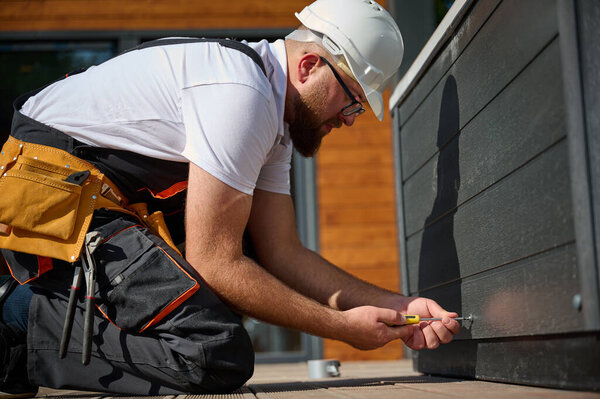 Plumber installing hot tub. Spa technician performing hot tub. Bathtub plumbing. Plumber fixing spa zone. Professional in uniform inspects and prepares a hot tub located on a stylish outdoor patio.