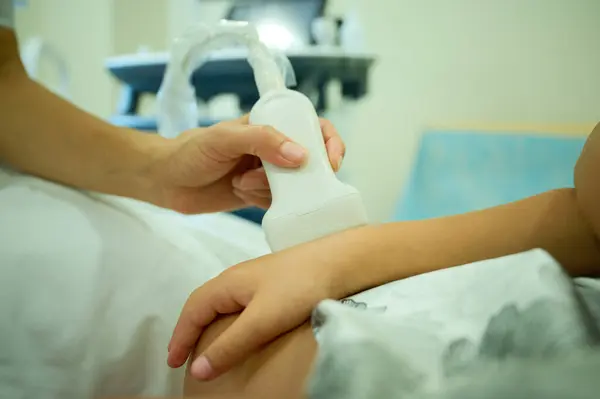 Doktor ultrason tarayıcısıyla bileği tarıyor. Eklem yaralanması. Çocuk travması. Ortopedist, kadının bileğinde ultrason sondası kullanıyor. Tendonların sonografisi. Kazadan sonra bilek ve eklem muayenesi