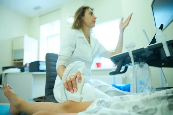 Pediatrik ultrason taraması. Çocuk ultrasonu. Çocuk doktoru bacağını tarıyor. Doktorun çocuk için bacak sonogramı yapmasına yakın çekim. İskelet sisteminin ultrason incelemesi. Eklem hastalıkları konsepti