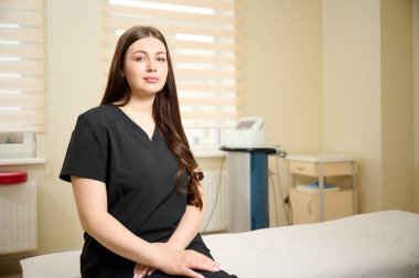 Klinikte tıp kıyafeti giymiş genç bir rehabilitasyon uzmanı kız. Yaralardan sonra iyileşme kavramı. Extracorporeal Shockwave Terapisi