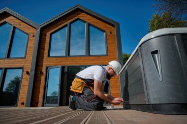 Tesisatçı jakuzi kuruyor. Kaplıca teknisyeni jakuzi yapıyor. Küvet tesisatı. Tesisatçı kaplıcayı tamir ediyor. Üniformalı bir uzman, şık bir bahçe avlusunda bir jakuzi hazırlıyor ve inceliyor..