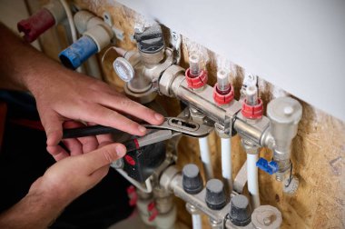 Adam yeni bir dairede ısıtma sistemini ayarlıyor. Tesisatçı merkezi sistem vanalarındaki ısıyı ayarlıyor. Servis elemanı ısıtma sistemini ayarlıyor. Yeraltı ısıtma sistemi. Ekin görünümü