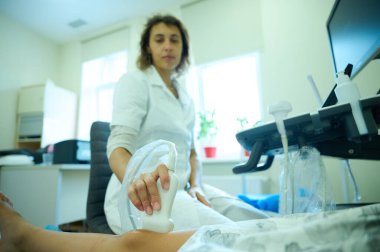 Pediatrik ultrason taraması. Çocuk ultrasonu. Çocuk doktoru bacağını tarıyor. Doktorun çocuk için bacak sonogramı yapmasına yakın çekim. İskelet sisteminin ultrason incelemesi. Eklem hastalıkları konsepti