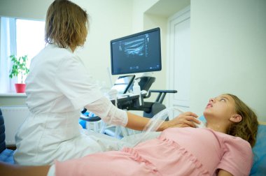 Doktorun çocuk için tiroit sonogramı yapmasına yakın çekim. Pediatrik ultrason taraması. Çocuk ultrasonu. Pediyatrist boynu tarıyor. Lenf düğümlerinin ultrason incelemesi. Çocukluk hastalıkları