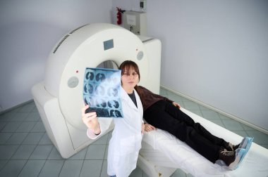 Tarama odasında hastası olan bir kadın radyolog. Tomografi odasında sevimli bir doktor. Radyolog, bilgisayarlı tomografi odasında bir kadın hasta ile birlikte. Modern klinik. Radyoloji Bölümü.