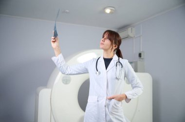 Genç bayan radyologlar tomografi odasında kalıyorlar. Klinikte çalışıyorum. Güzel doktor röntgen, röntgen, tomografi ve MRI 'ya bakıyor. Üniformalı doktor.