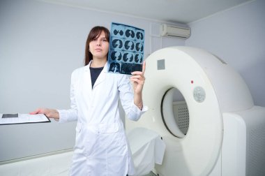 Genç bayan radyologlar tomografi odasında kalıyorlar. Klinikte çalışıyorum. Güzel doktor röntgen, röntgen, tomografi ve MRI 'ya bakıyor. Üniformalı doktor.