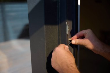 Yeni bir inşaat sahasına kapı ve pencere döşeyen işçilerin yakın görüntüsü. Büyülü anahtarı olan üniformalı bir adam yeni güzel evin ön cam kapısını ve pencerelerini ayarlıyor. Ekin görünümü.