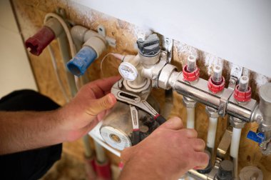 Adam yeni bir dairede ısıtma sistemini ayarlıyor. Tesisatçı merkezi sistem vanalarındaki ısıyı ayarlıyor. Servis elemanı ısıtma sistemini ayarlıyor. Yeraltı ısıtma sistemi. Ekin görünümü
