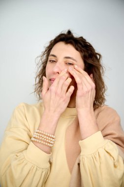 Yüz hatlarını güçlendirmek için yüz egzersizleri yapan beyaz bir kadının portresi. Yüz derisinin tazelenmesi kavramı. Cerrahi olmayan yüz kaldırma. Yüz geliştirme.