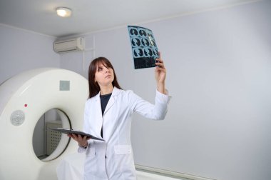 Genç bayan radyologlar tomografi odasında kalıyorlar. Klinikte çalışıyorum. Güzel doktor MRI taramasına bakıyor. Beyaz takım elbiseli bir doktor. Üniformalı Radyolog.