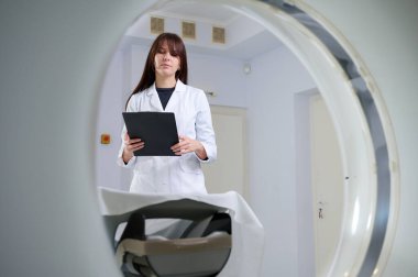 Genç bayan radyologlar tomografi odasında kalıyorlar. Klinikte çalışıyorum. Güzel doktor röntgen, röntgen, tomografi ve MRI 'ya bakıyor. Üniformalı doktor.