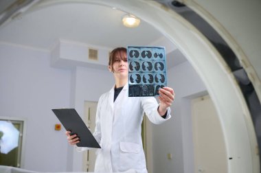 Genç bayan radyologlar tomografi odasında kalıyorlar. Klinikte çalışıyorum. Güzel doktor röntgen, röntgen, tomografi ve MRI 'ya bakıyor. Üniformalı doktor.