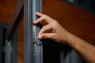 Yeni bir inşaat sahasına kapı ve pencere döşeyen işçilerin yakın görüntüsü. Büyülü anahtarı olan üniformalı bir adam yeni güzel evin ön cam kapısını ve pencerelerini ayarlıyor. Ekin görünümü.