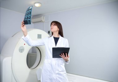 Genç bayan radyologlar tomografi odasında kalıyorlar. Klinikte çalışıyorum. Güzel doktor MRI taramasına bakıyor. Beyaz takım elbiseli bir doktor. Üniformalı Radyolog.