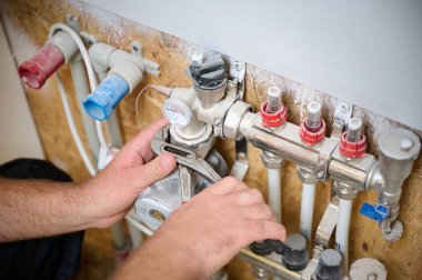 Adam yeni bir dairede ısıtma sistemini ayarlıyor. Tesisatçı merkezi sistem vanalarındaki ısıyı ayarlıyor. Servis elemanı ısıtma sistemini ayarlıyor. Yeraltı ısıtma sistemi. Ekin görünümü