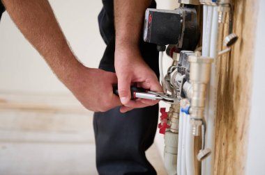 Adam yeni bir dairede ısıtma sistemini ayarlıyor. Tesisatçı merkezi sistem vanalarındaki ısıyı ayarlıyor. Servis elemanı ısıtma sistemini ayarlıyor. Yeraltı ısıtma sistemi. Ekin görünümü