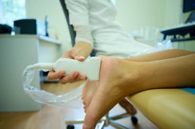 Pediatrik ultrason taraması. Çocuk ultrasonu. Çocuk doktoru bacağını tarıyor. Doktorun çocuk için bacak sonogramı yapmasına yakın çekim. İskelet sisteminin ultrason incelemesi. Eklem hastalıkları konsepti