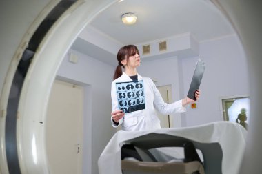 Genç bayan radyologlar tomografi odasında kalıyorlar. Klinikte çalışıyorum. Güzel doktor röntgen, röntgen, tomografi ve MRI 'ya bakıyor. Üniformalı doktor.