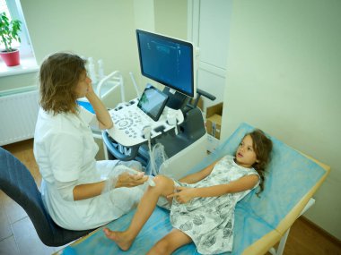 Pediatrik ultrason taraması. Çocuk ultrasonu. Çocuk doktoru bacağını tarıyor. Doktorun çocuk için bacak sonogramı yapmasına yakın çekim. İskelet sisteminin ultrason incelemesi. Eklem hastalıkları konsepti