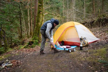 Ormandaki çadırın yakınındaki ilk yardım çantasını kullanan yaralı bacaklı bir yürüyüşçü. Stresli bir yürüyüşçü dağda kırık diziyle tek başına şikayet ediyor..