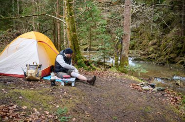 Ormandaki çadırın yakınındaki ilk yardım çantasını kullanan yaralı bacaklı bir yürüyüşçü. Stresli bir yürüyüşçü dağda kırık diziyle tek başına şikayet ediyor. Gezgin yaralanmadan sonra bacağını bandajlıyor.