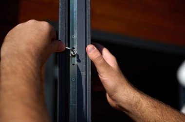 Yeni bir inşaat sahasına kapı ve pencere döşeyen işçilerin yakın görüntüsü. Büyülü anahtarı olan üniformalı bir adam yeni güzel evin ön cam kapısını ve pencerelerini ayarlıyor. Ekin görünümü.