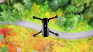 Drone ormanın üzerinde uçuyor. Kara kuadkopter bir orman yolunun üzerinde havada süzülüyor. Üst görünümü uçur