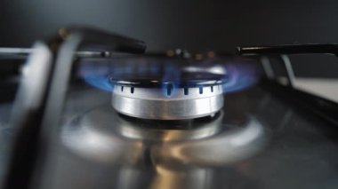 Yakıcının üzerinde gaz kontağı var, yakın plan. Mutfak gaz ocağında doğal gaz yanıyor.