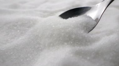 Granüle edilmiş beyaz şeker. Kaşık beyaz şeker toplar.