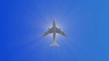 Parlak güneşin karşısında, tepemizde uçan bir uçak. Açık mavi gökyüzünde uçan uçaklar