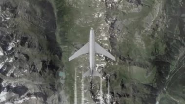 Dağların üzerinden uçak, tepeden manzara. Ticari ya da kargo uçağı yüksek hızda uçuyor, el kamerasıyla çekiliyor.