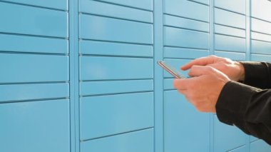 Paket dolabı cep telefonuyla açılıyor. Otomatik indirme noktasının önünde bir paket alınır