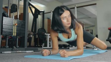 Sportif kadın spor salonunda temel karın kuvveti egzersizi yapıyor..