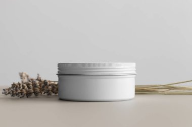 Beyaz kozmetik krem kavanozu. Bej masasında lavanta var..