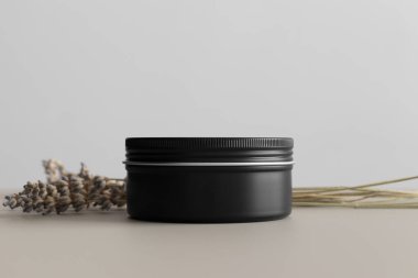 Siyah kozmetik krem kavanozu. Bej masasında lavanta var..