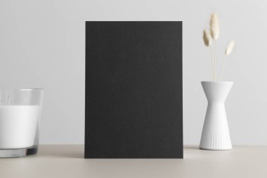 Siyah davetiye modeli, lagurus süslemesi ve bej masasında bir mum. 5x7 oranı, A6, A5 'e benziyor..
