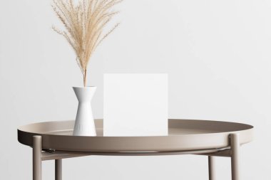 Kare davetiye maketi. Bej masa üzerinde kurumuş çiçek süslemesi..