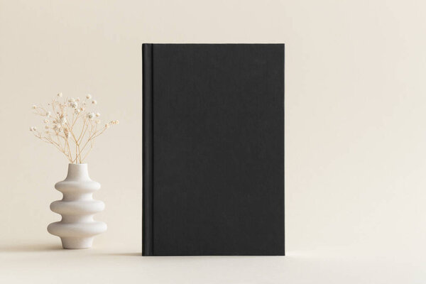 Black book mockup with a gypsophila decoration on the soft yellow background.
