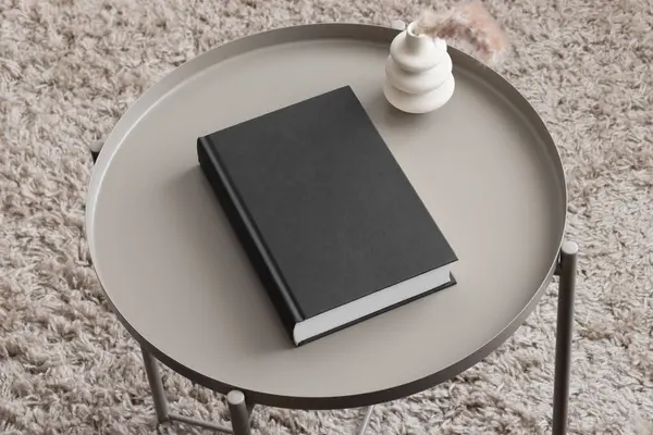 Black book mockup with a pampas decoration on the beige table.