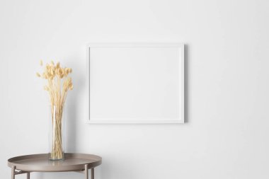 Beyaz çerçeve, duvarda kurumuş bir çiçek süslemesiyle..